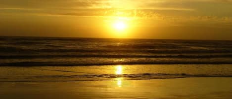 A sunset over the ocean with waves reflecting the sunlight.