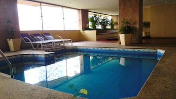 Una piscina techada, sillones reclinables de piscina