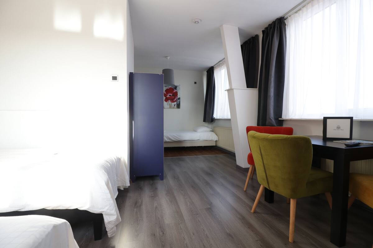 A hotel room with a bed, a desk, a chair, and a window with curtains.
