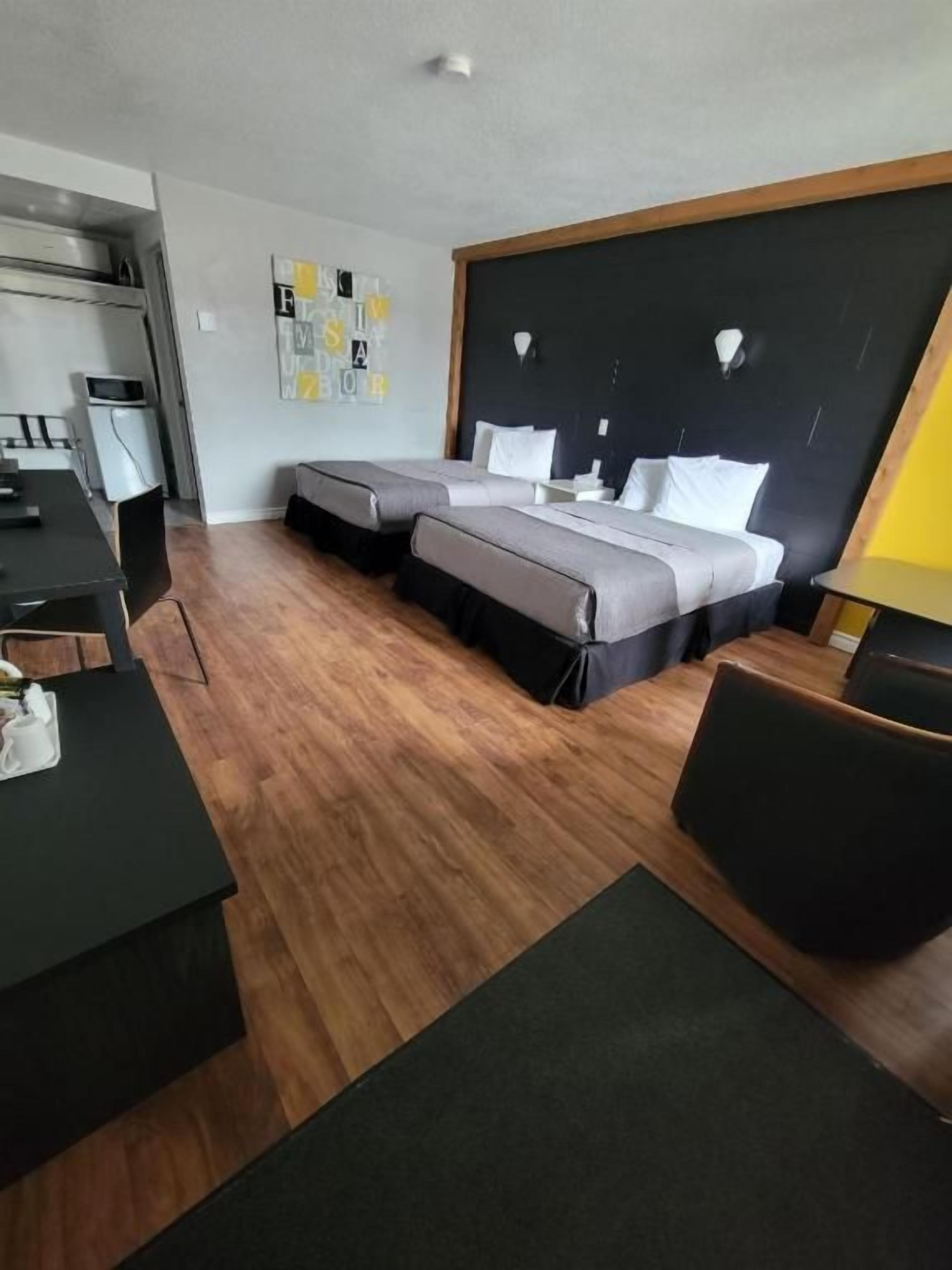 Una habitación de hotel con cama, escritorio, silla y una mesita.