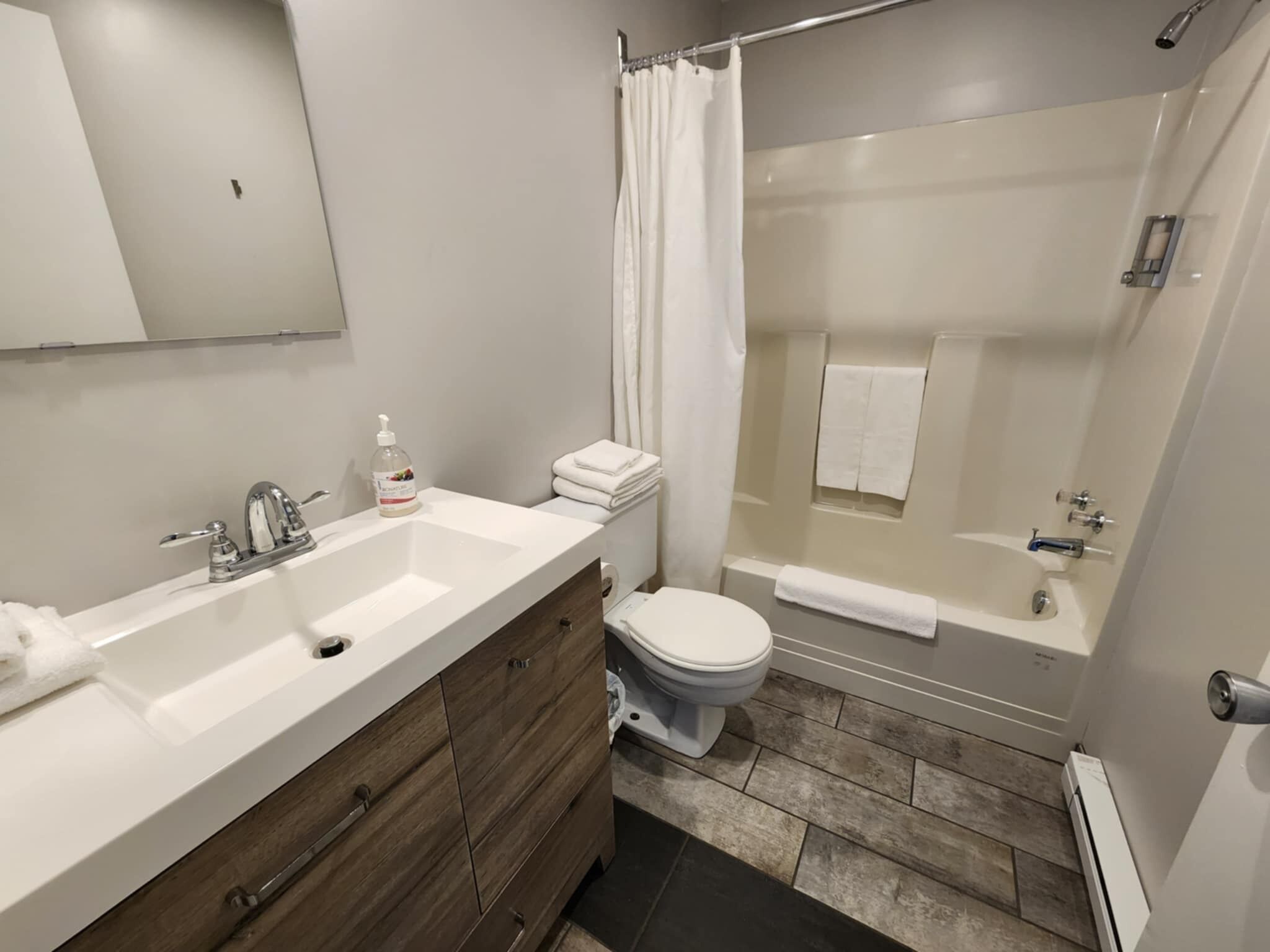 A modern bathroom with a dual sink vanity, a toilet, a shower with a glass door, and a towel rack.