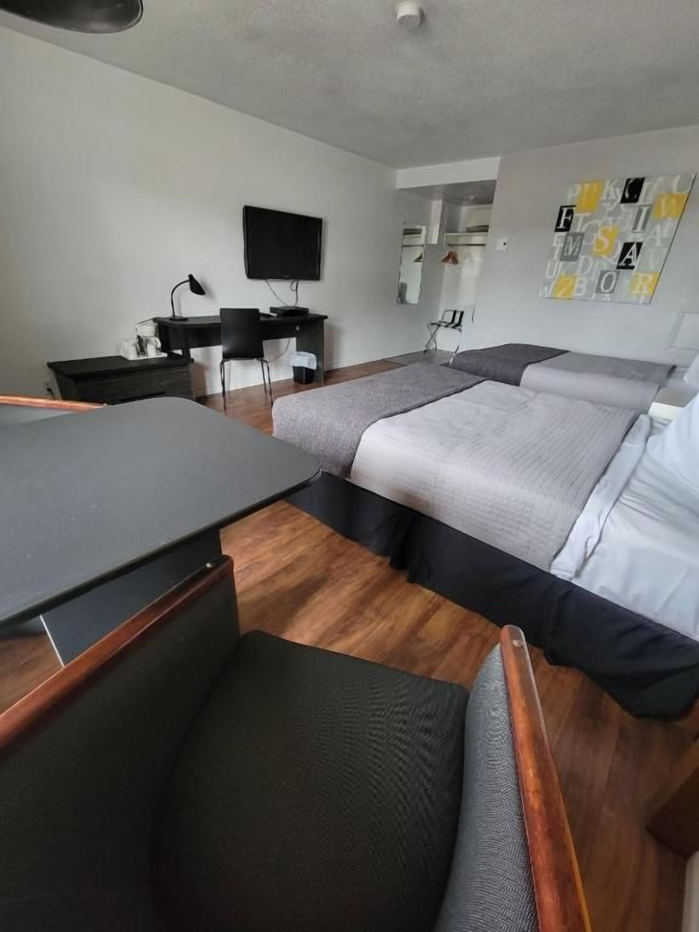 Habitación de hotel con dos camas, un escritorio, una silla, un televisor y un espejo.