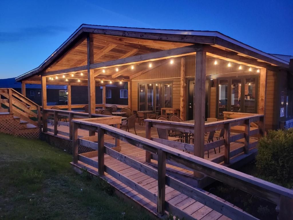 A wooden building with a covered patio area, outdoor seating, and a staircase leading to the entrance.