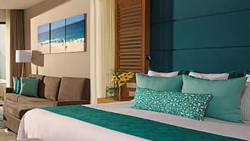 A hotel room with a large bed, a bench, a sofa, and a painting of a beach scene.