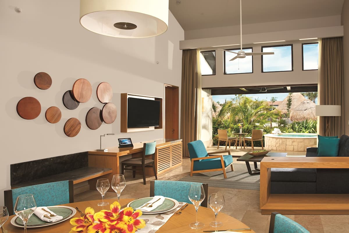 A modern hotel room with a dining area, a TV, and a view of the outdoors.