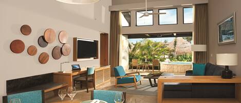 A modern hotel room with a dining area, a TV, and a view of the outdoors.