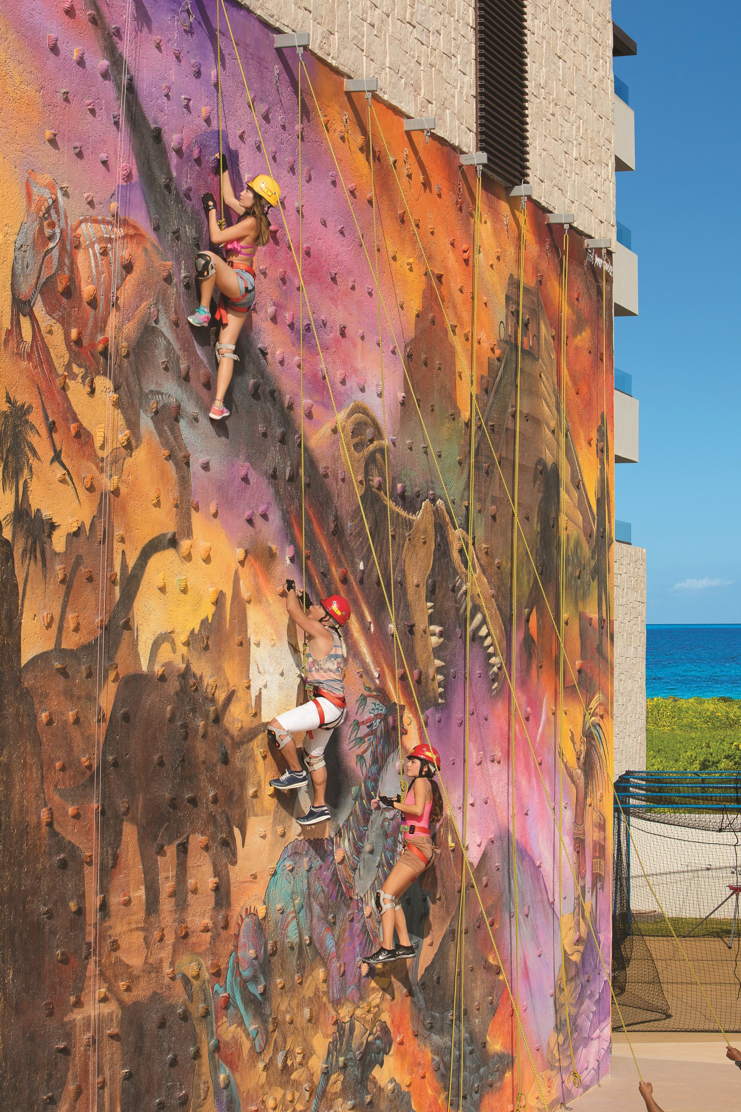 Una pared de escalada con un mural de animales prehistóricos.