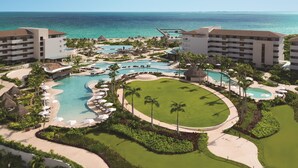 Un resort con varias piscinas, campo de golf y vistas a la playa.