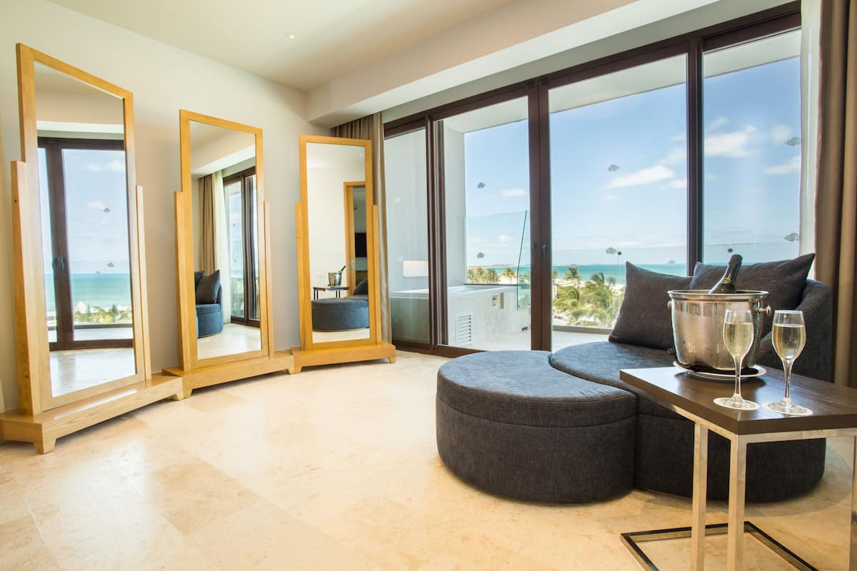 A modern hotel room with a large balcony, a seating area with a table, and a large mirror.