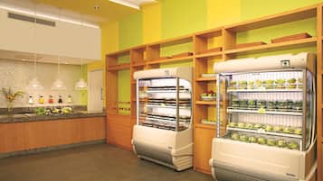 Una panadería con dos vitrinas repletas de productos horneados y un mostrador con frutas y verduras frescas.