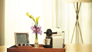 Une machine à café sur un plateau, accompagnée d’un menu, d’un vase avec des fleurs et d’une lampe en arrière-plan.