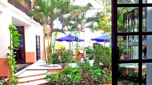 A courtyard with a staircase leading to a door, surrounded by lush greenery and blue umbrellas. - Canadian Resorts Huatulco (Santa María Huatulco)