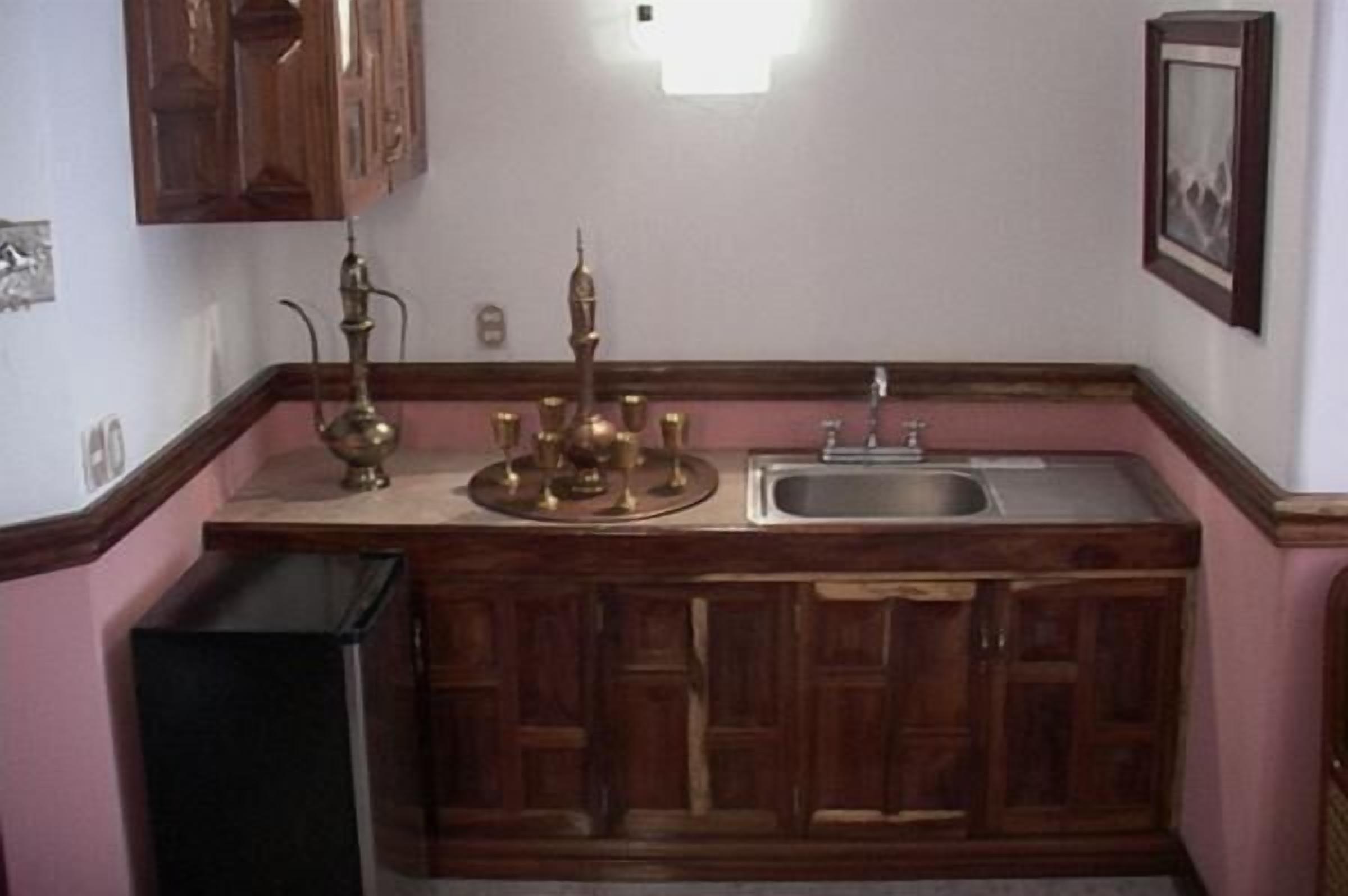 Une cuisine avec des meubles en bois, un évier et un joli service à thé en laiton.