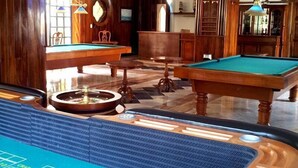 A pool table with a blue felt surface and a roulette wheel in the foreground. - Canadian Resorts Huatulco (Santa María Huatulco)