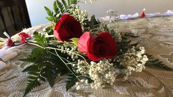 A bouquet of red roses and baby's breath on a patterned tablecloth.