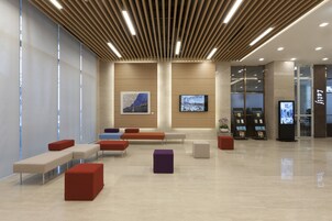 Un hall moderno con zonas de estar, un mostrador de recepción y pantallas digitales.