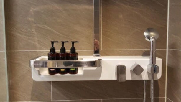 A bathroom with a shower, a soap dispenser, and a hand dryer.