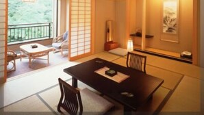 Una habitación tradicional japonesa con suelo de tatami, una mesa baja con cojines y puertas correderas.