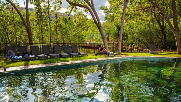 A swimming pool with clear water, surrounded by lounge chairs and trees. - El Questro - Emma Gorge (Durack)