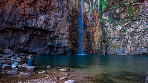 A waterfall cascading down a rocky cliff into a clear pool of water. - El Questro - Emma Gorge (Durack)