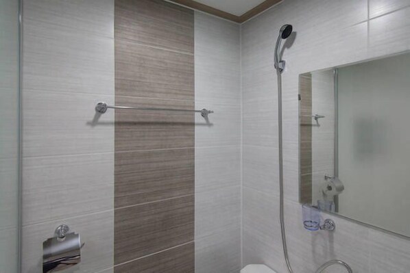 Une salle de bain avec douche, toilettes et porte-serviettes.