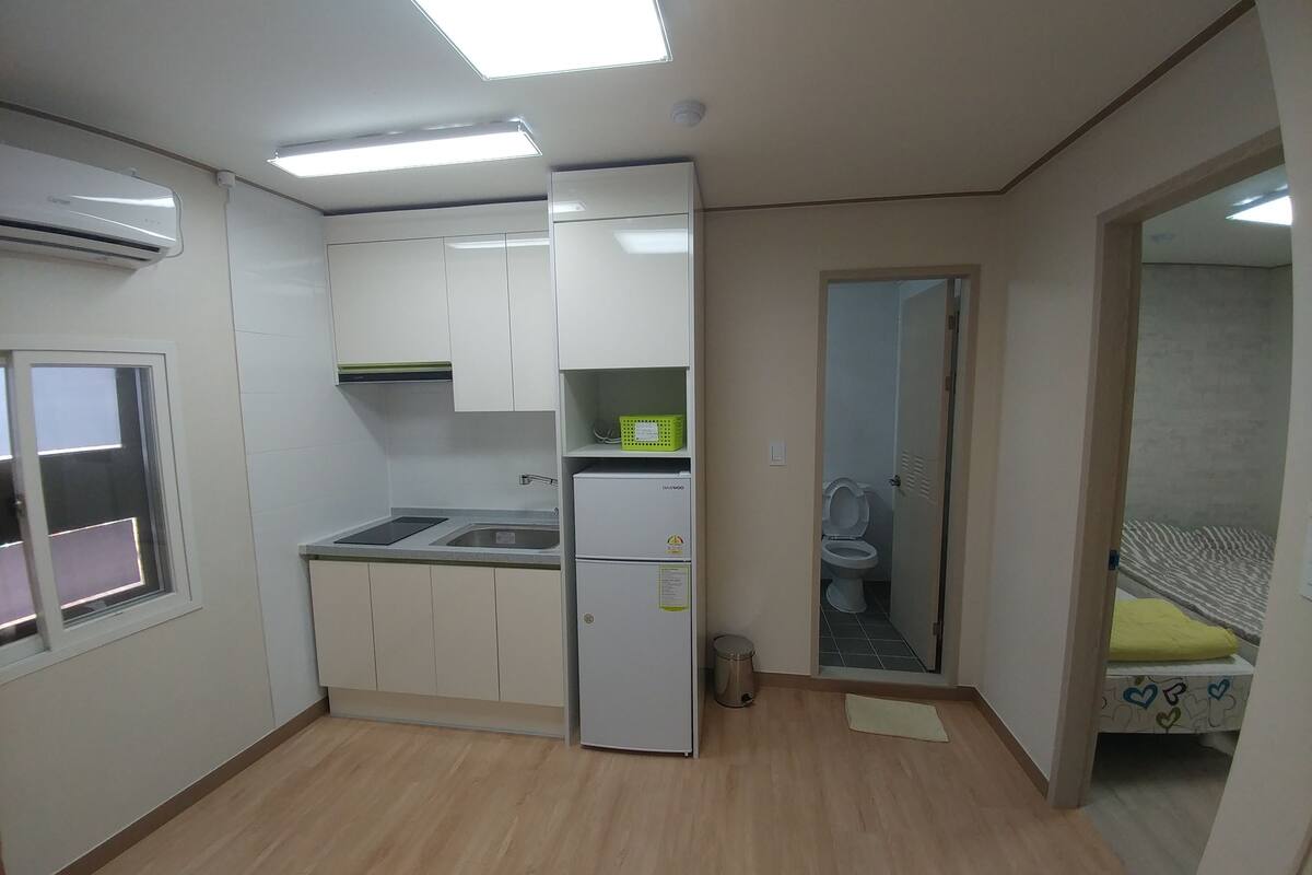 A compact kitchen with white cabinets, a built-in sink, and a refrigerator.