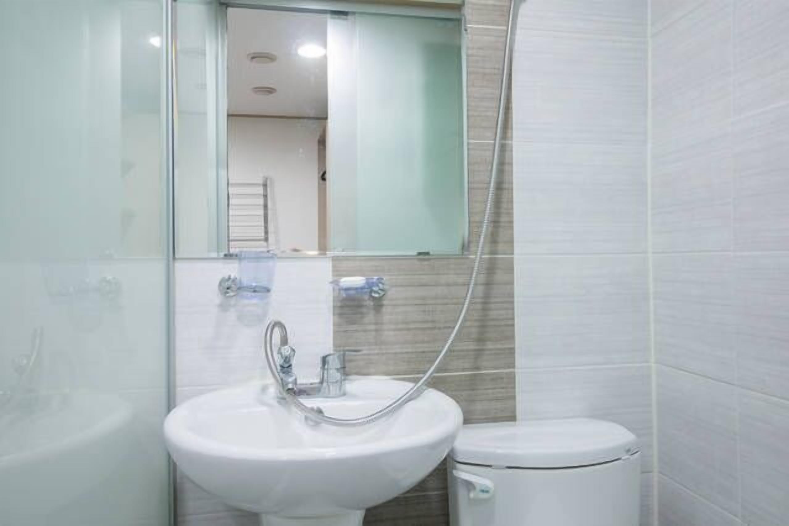 A bathroom with a white sink, a mirror, and a toilet.