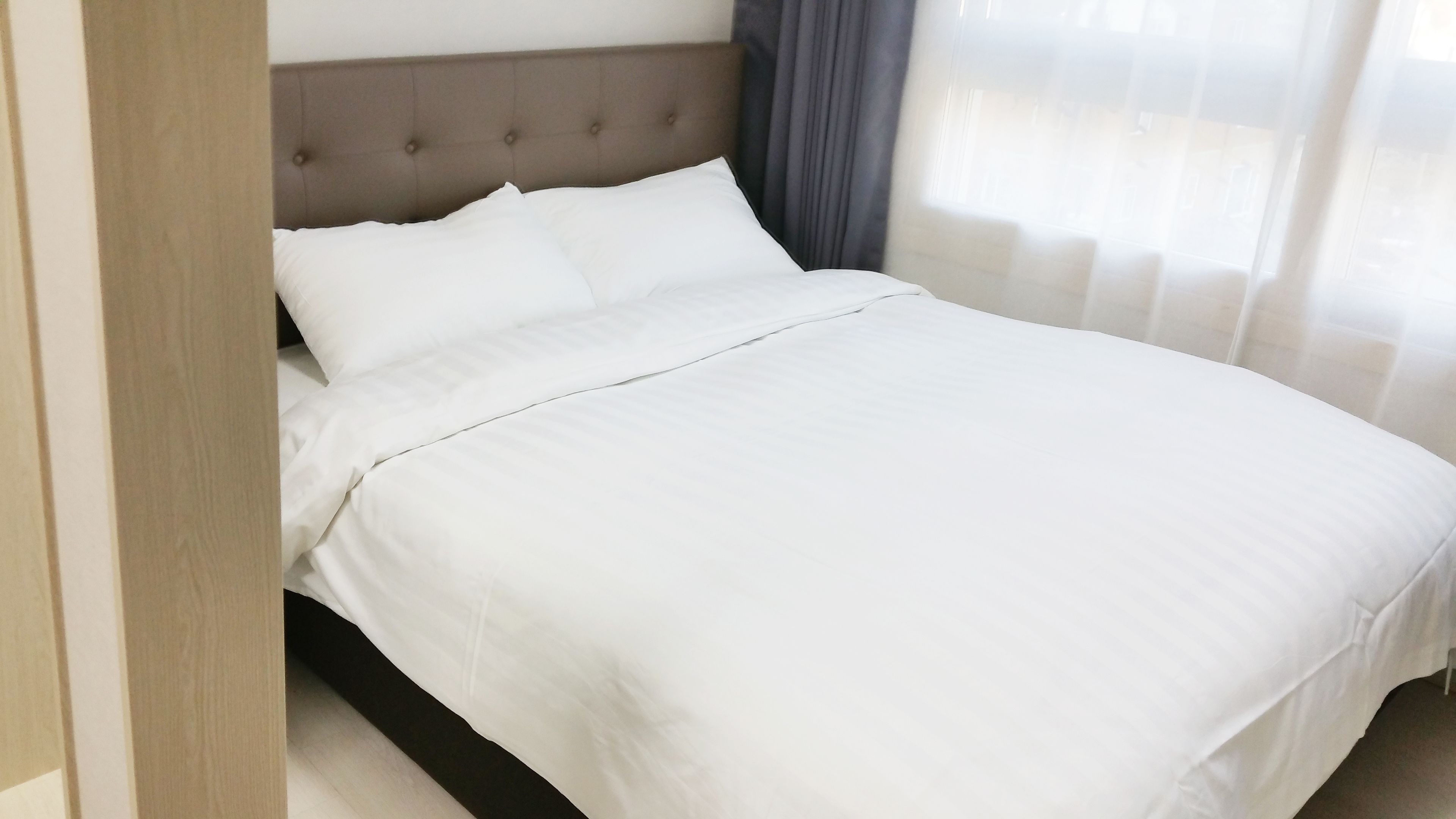Uma cama bem arrumada com roupa de cama branca em um quarto de hotel.