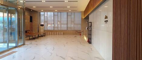 A spacious lobby with a marble floor, large windows, and a reception desk.