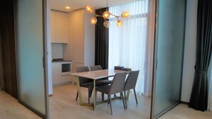 A modern dining area with a table and chairs, a kitchen in the background, and a large window with curtains. - Am Hotel (Pyeongchang)