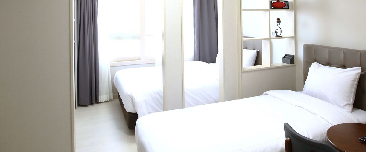 Une chambre d’hôtel avec deux lits, une petite table et une étagère ornée d’objets décoratifs.