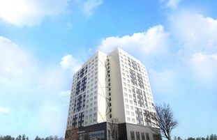 A high-rise building with multiple floors, large windows, and a clear sky.
