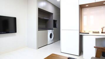 Uma cozinha moderna com eletrodomésticos embutidos, televisão de tela plana e um pequeno espaço de estar.