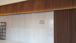 A hotel reception area with a modern design, featuring a large sign with the hotel's logo and name. - Am Hotel (Pyeongchang)