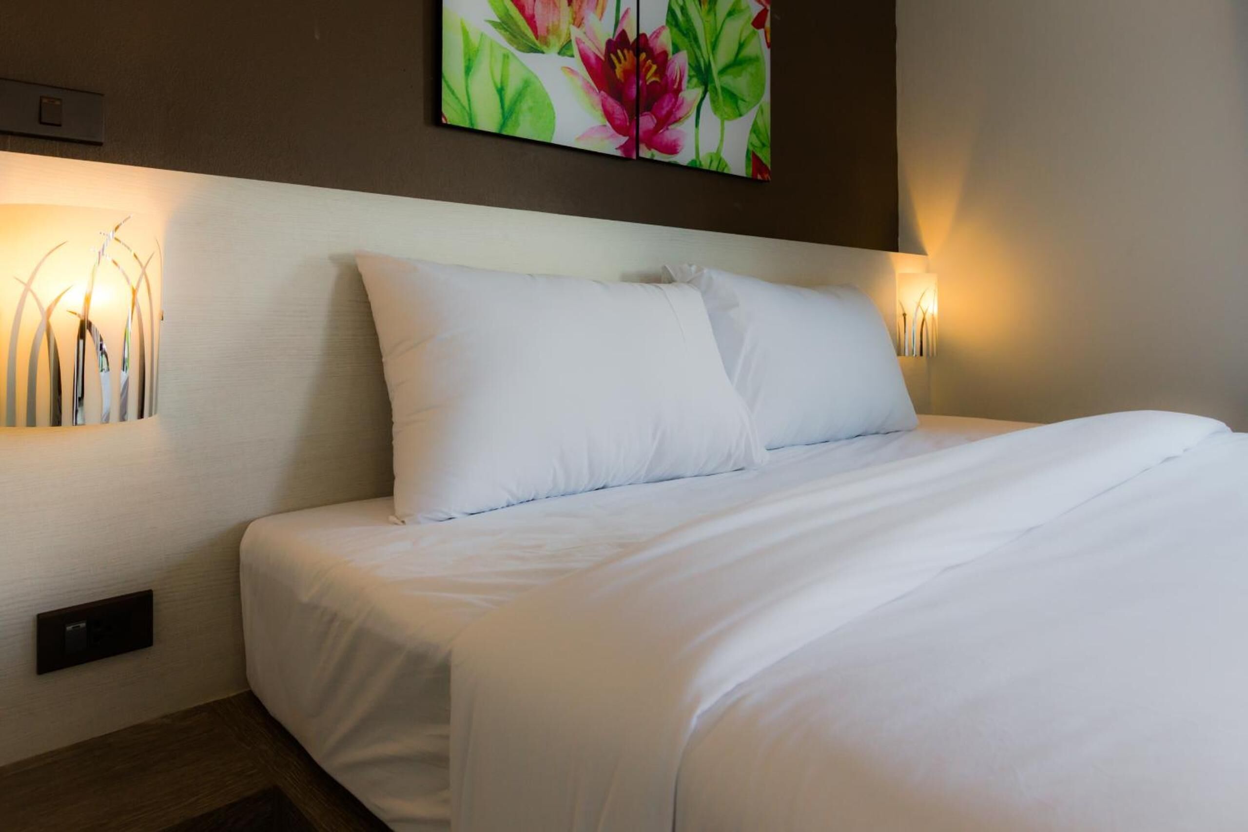 Una cama bien hecha con sábanas blancas en una habitación de hotel.