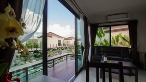 A modern living room with a large window overlooking a koi pond and a residential area. - Bua Tara Resort (Pattaya)