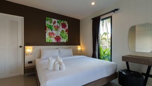A modern bedroom with a large bed, a bedside table, a mirror, and a view of greenery outside. - Bua Tara Resort (Pattaya)
