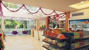 Een hotel lobby met een receptiebalie, een zithoek en diverse verpakte producten op planken.