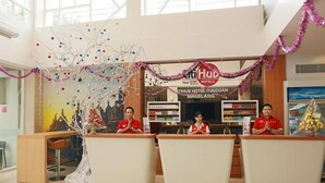Een receptiebalie met drie medewerkers, een kerstboom en een bord met de tekst 'iHub Hotel @JAGOAN MAGELANG'.