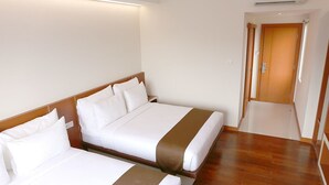 Een hotelkamer met twee bedden, houten vloeren en een airconditioning op de muur.