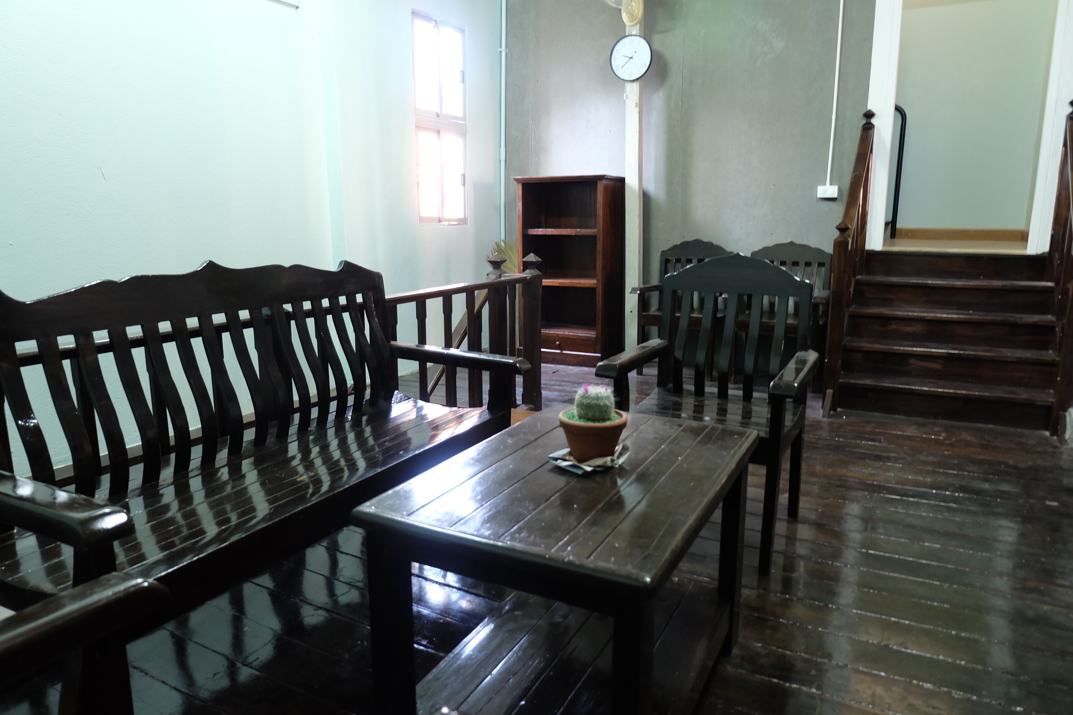 A room with a wooden bench, a small table with a potted plant, and a staircase.