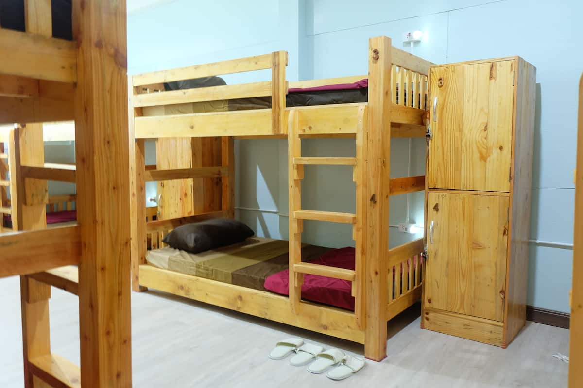 A bunk bed with a wooden ladder and a small cabinet.