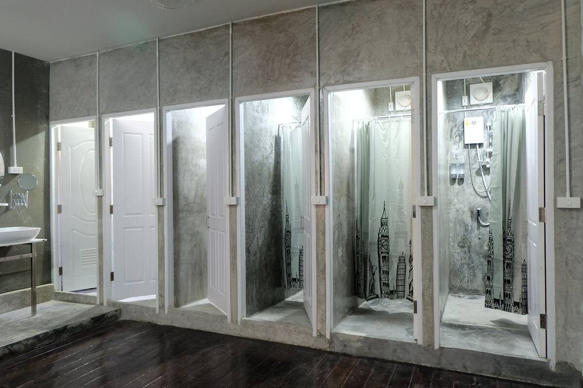 A bathroom with multiple shower stalls, each with a glass door and a mirror above.
