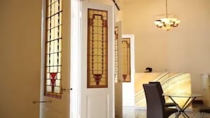 A hotel room with a large window, a chandelier, and a marble accent wall. - Alimar Hotel (Malang)