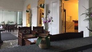 A spacious lobby with a high ceiling, a reception desk, and a seating area with wooden furniture. - Alimar Hotel (Malang)