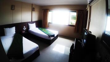 A hotel room with two beds, a desk, and an air conditioning unit.