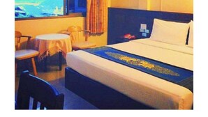 A hotel room with a bed, a desk, two chairs, a window with curtains, and a view of the outdoors. - Chiangkhong Green Inn Residence (Chiang Khong)