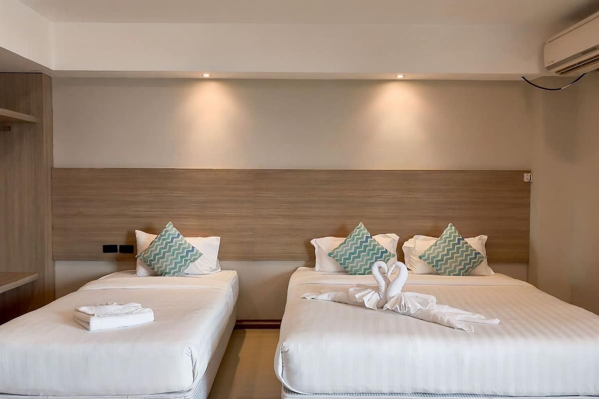 A hotel room with two beds, each with white linens and decorative pillows.