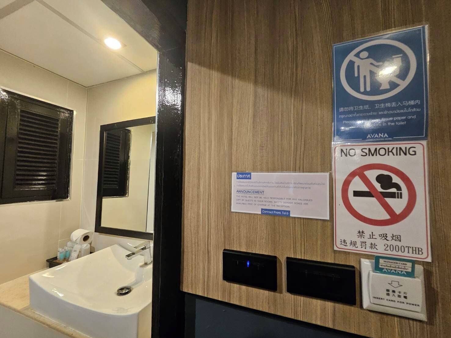 A hotel bathroom with a sink, mirror, and a no smoking sign.