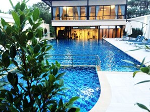Uma área de piscina moderna com vista desobstruída, uma escadaria para um nível superior e cadeiras de descanso à direita.
